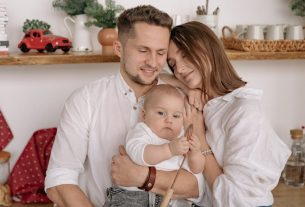 A joyful family of three embracing in a cozy kitchen. Warm and loving atmosphere.